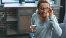 A Woman Sweating While Holding a Glass of Water and Rubbing Her Forehead Is Hormone Replacement Therapy Safe